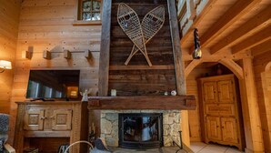A wooden interior with a stone fireplace, wooden cabinets, and a television on a wooden shelf. - Chalet Glaciers | Fireplace | View | Comfy | Quiet (Les Houches)
