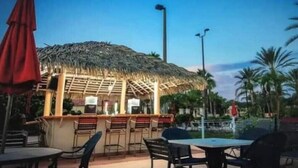 An outdoor bar area with a thatched roof, bar stools, and tables. - Perfect place for a relaxing family getaway!
 (Davenport)