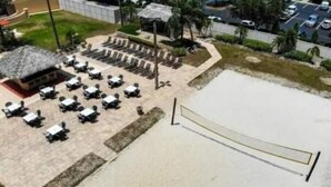 An outdoor seating area with tables and chairs, a volleyball net, and a small building with a thatched roof. - Perfect place for a relaxing family getaway!
 (Davenport)