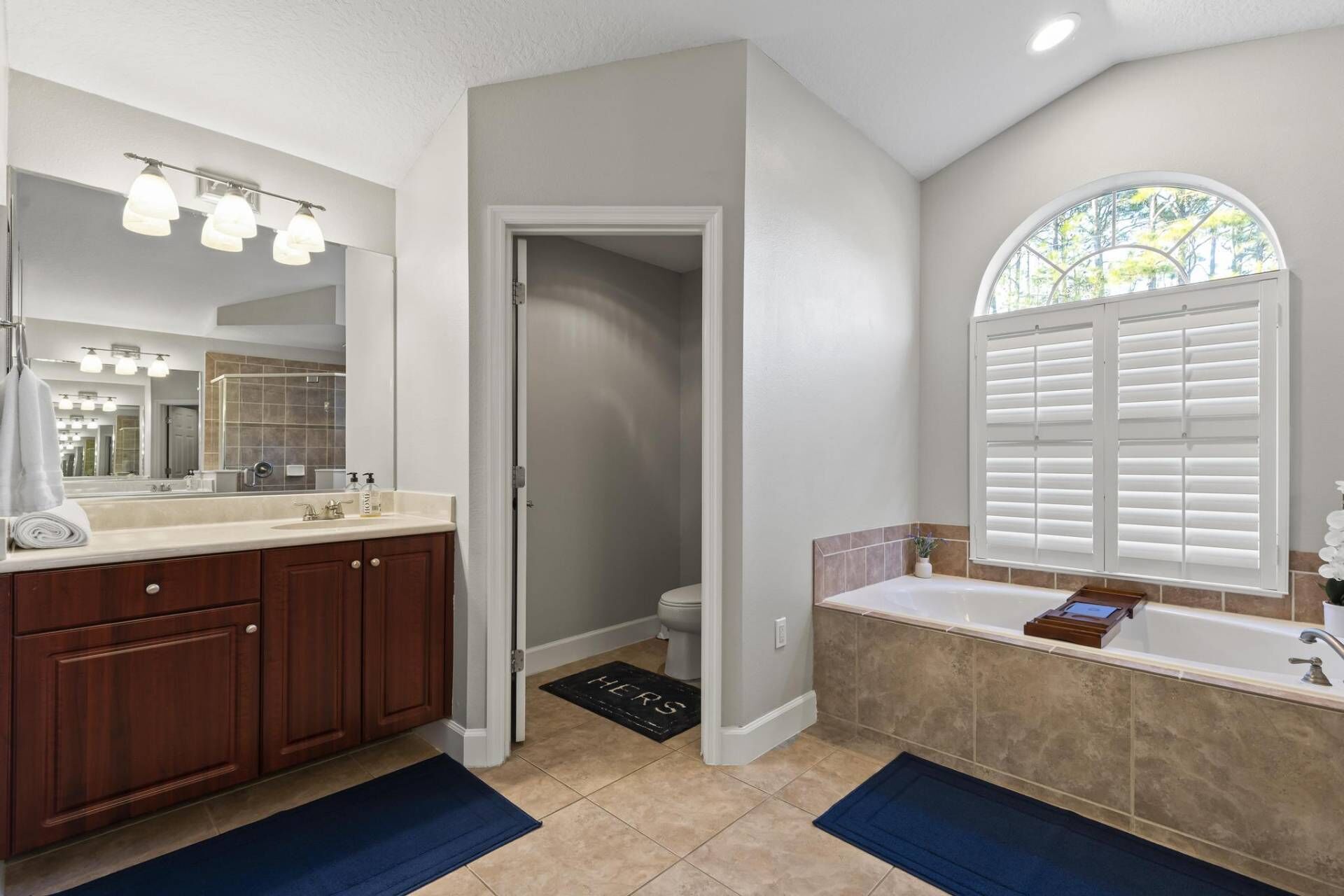 A bathroom with a large mirror, vanity, and a bathtub.
