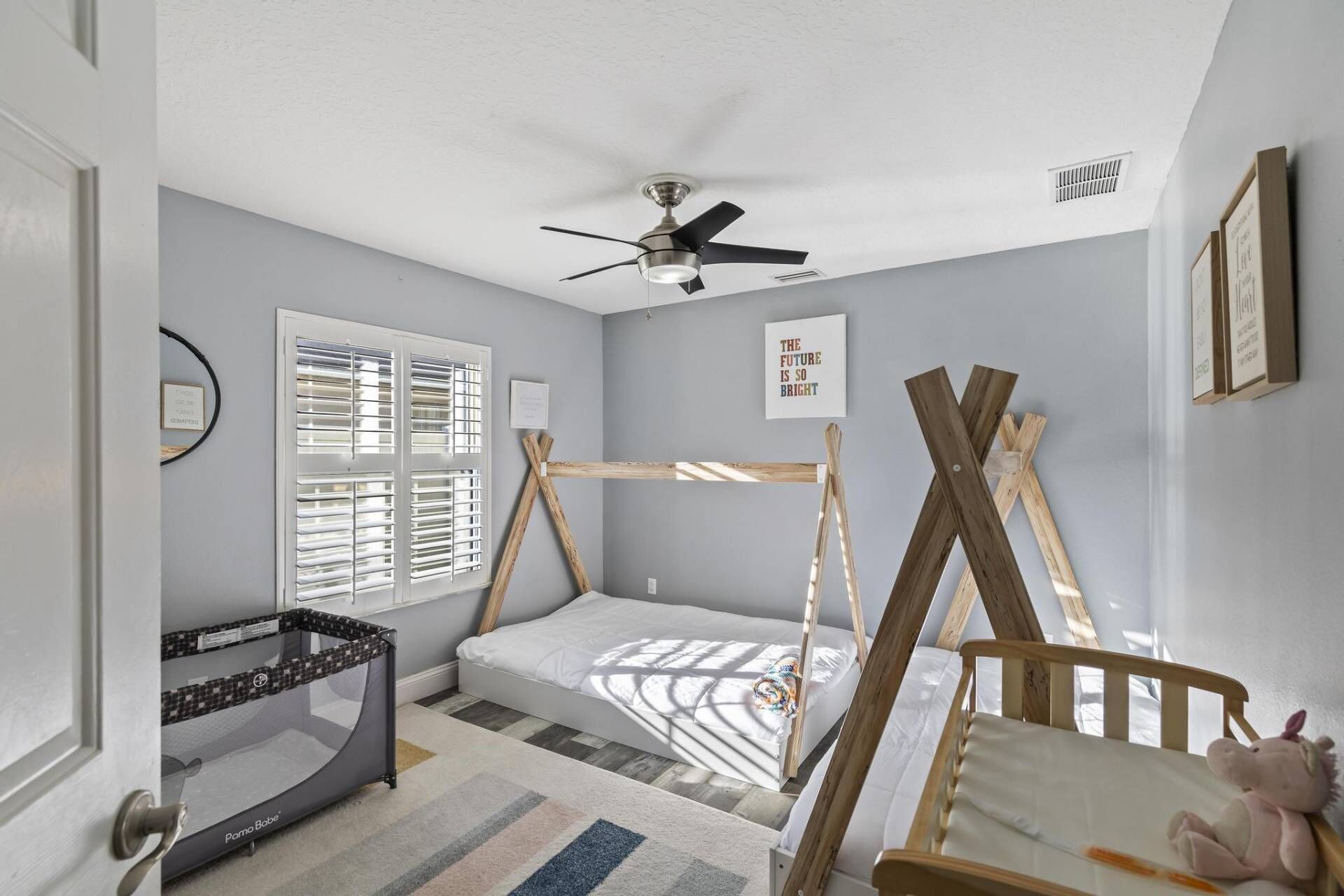 A child's bedroom with a bed, a playpen, and a crib.