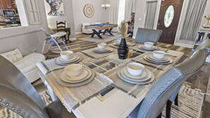 Un comedor con una mesa rectangular dispuesta para cuatro personas, rodeada de sillas tapizadas con tachuelas metálicas.