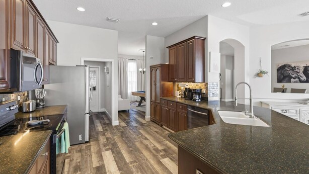 Una cocina moderna con armarios de madera, encimera de granito y refrigerador de acero inoxidable.