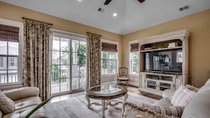 A living room with a sofa, a glass coffee table, a television, and a cabinet. - Stunning Home w Private Pool in North Beach Resort & Villas - Only 150 Yards to Pools/Beach! (North Myrtle Beach)