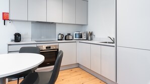 A modern kitchen with white cabinets, a Bosch oven, a microwave, a toaster, and a sink.