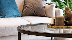 A modern living room with a beige sofa, a round glass coffee table, and a large green plant. - St Martin's Place - Birmingham City Centre (Birmingham)