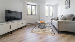 A modern living room with a flat-screen TV, a sofa, a coffee table, and a patterned rug. - Sevenstays Residences Solihull - NEC / Airport (Solihull)