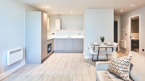Une cuisine moderne dotée d’un îlot central, de meubles blancs et d’un coin repas avec une table et des chaises.