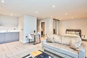 Un appartement moderne comprenant un coin cuisine, un espace repas, un salon avec un canapé et un lit.