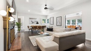 A spacious living room with a large gray sectional sofa, a dining area with wooden chairs, and a fireplace with a modern design. - Brookside- One of a Kind (Tulsa)