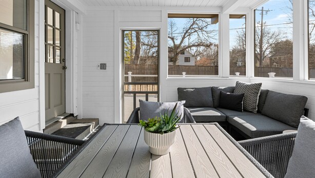 A covered porch with a wooden table, a cushioned seating area, and a potted plant. - Brookside- One of a Kind (Tulsa)