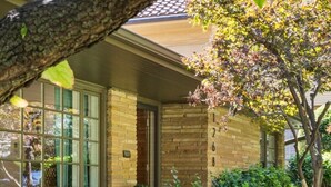 A house with a brick exterior, large windows, and a well-maintained garden with a tree and shrubs. - Brookside- One of a Kind (Tulsa)