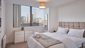 A modern hotel room with a large bed, a bedside table, a window with a view of the cityscape, and a ceiling light. - Sevenstays Bham City Centre, 1 bed - Free Parking (Birmingham)