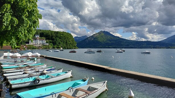 A marina with boats docked, a dock extending into calm water, and a mountain in the background. - Beau Chalet Rénové, Avec vue Imprenable sur les Montagnes (Dingy-Saint-Clair)