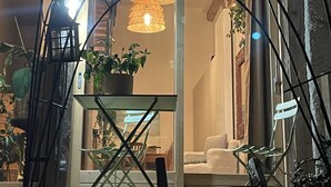 A modern outdoor seating area with a glass door entrance, a metal table, and two hanging wicker lamps. - Beau Chalet Rénové, Avec vue Imprenable sur les Montagnes (Dingy-Saint-Clair)