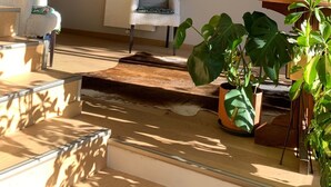 A cozy living room with a wooden ceiling, a white sofa, a chair, and various potted plants. - Beau Chalet Rénové, Avec vue Imprenable sur les Montagnes (Dingy-Saint-Clair)
