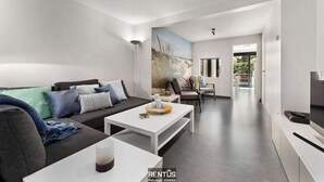 A modern living room with a sofa, coffee table, and a painting on the wall. - Sasea - ground floor apartment with garden (Nieuwpoort)