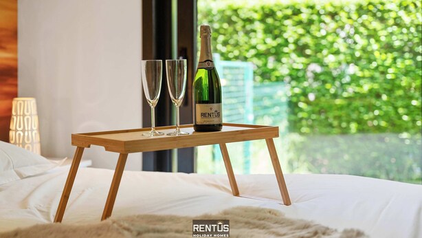 A bed with a wooden nightstand holding a bottle of wine and two glasses. - Sasea - ground floor apartment with garden (Nieuwpoort)
