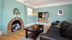 Una sala de estar con chimenea, televisor, sofá y estantería.