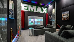 Ein modernes Heimkino mit großer Leinwand, bequemen Sitzen und einer digitalen Bedienoberfläche zur Filmauswahl.