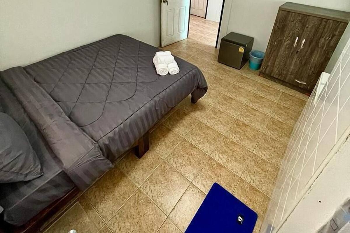 Un dormitorio con cama, armario, puerta y un tapete azul en el suelo.