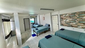 A hotel room with three beds, a tiled floor, a stone wall, and a door. - 56 Chiang Mai Soi 3 (Chiang Mai)