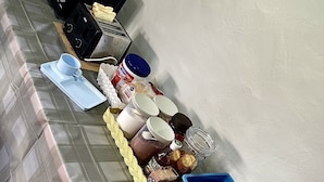 A dining table with a microwave, toaster, and various food items including fruits and condiments. - 56 Chiang Mai Soi 3 (Chiang Mai)