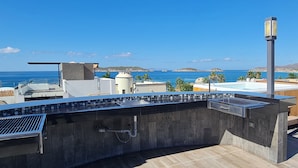 Eine Außenküche mit Blick auf das Meer, ein Pool und ein Berg im Hintergrund.