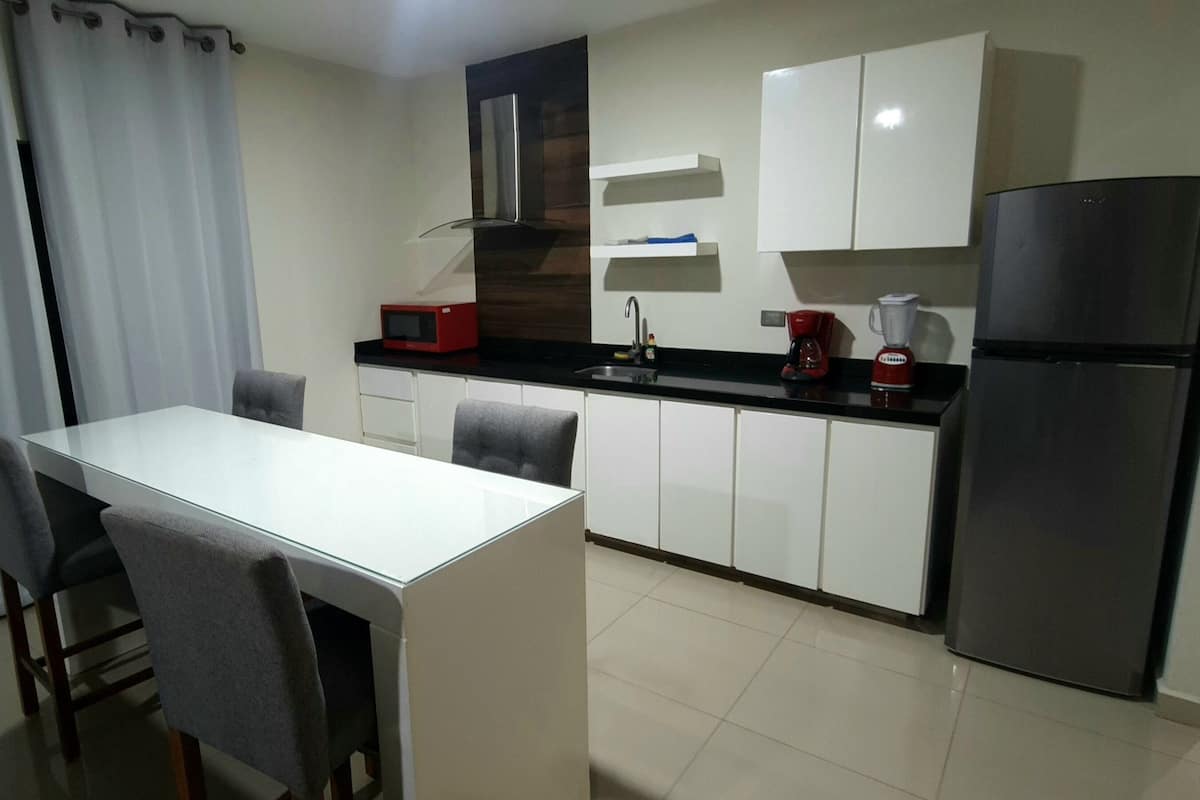 A compact kitchen with a white countertop, a black refrigerator, a microwave, and a coffee maker.