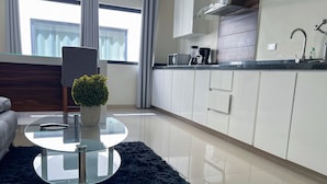 Eine moderne Küche mit weißen Schränken, einer schwarzen Arbeitsplatte und einem Glastisch mit einem Blumentopf.