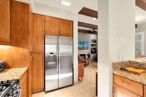 Une cuisine moderne avec des meubles en bois, un réfrigérateur en acier inoxydable, une cuisinière à gaz et un plan de travail en granit.