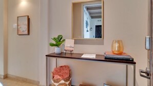 A reception desk with a mirror, a potted plant, a glass vase, and a framed picture. - Desert Daydream C | Studio Legacy Villa (La Quinta)