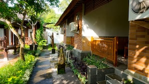 A traditional courtyard with stone pathways, wooden furniture, and lush greenery. - La Nusa Penida Homestay (Penida Island)