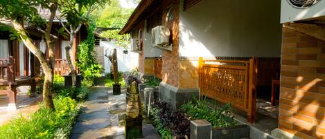 A traditional courtyard with stone pathways, wooden furniture, and lush greenery.