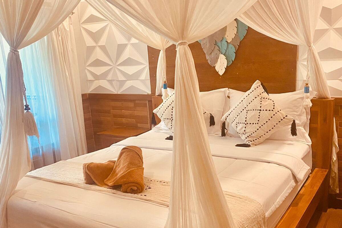 A bed with a canopy, a wooden headboard, and a geometric wall design.