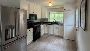 A modern kitchen with stainless steel appliances, white cabinetry, and a large window providing a view of the outdoors. - Acre Inn- private countryside home south of Nashville, 15 min to Spring Hill (Spring Hill)
