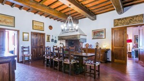 A rustic dining area with a large wooden table and chairs, a stone fireplace, and wooden beams on the ceiling. - I Cancelli by Interhome (Florence)