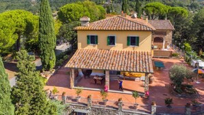 A villa with a tiled roof, a patio area, and a view of the surrounding hills. - I Cancelli by Interhome (Florence)