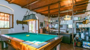A pool table in a room with a brick ceiling and wooden beams, a bookshelf filled with books, and a radiator. - I Cancelli by Interhome (Florence)