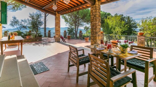 A covered outdoor patio with wooden furniture and a view of the landscape. - I Cancelli by Interhome (Florence)