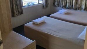 A room with two beds, a wooden dresser, and a window with curtains. - Cairns holiday unit apartment kitchen aircon wifi near esplanade and hospital (Cairns North)