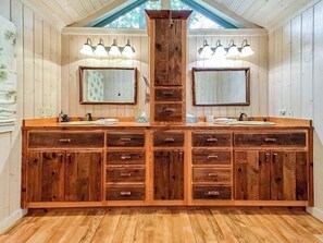 A wooden vanity with two mirrors, a central sink, and multiple drawers.