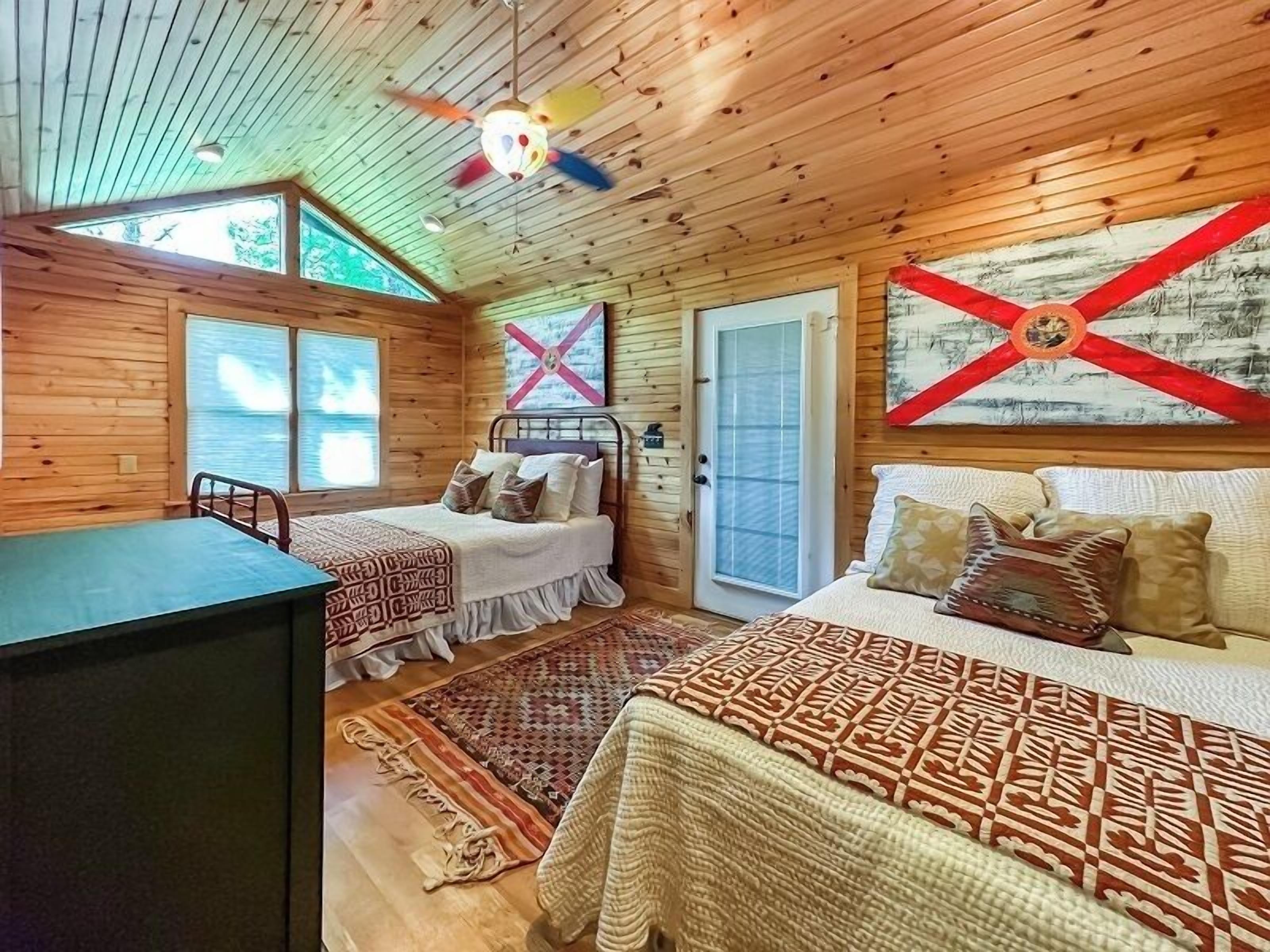 A cabin with two beds, a desk, and a ceiling fan.
