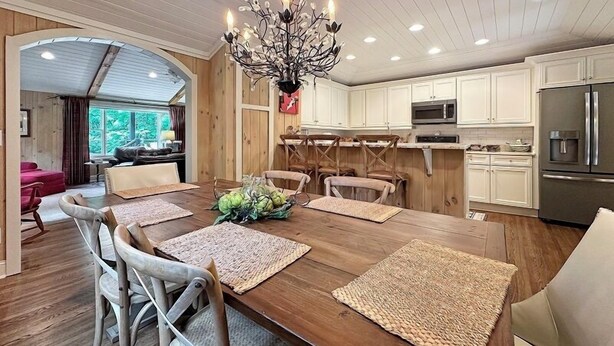 A modern kitchen with white cabinets, a stainless steel refrigerator, and a chandelier. - Walk to Dinner. Walk to Coffee. Walk to Everything | Wilson Cottage (Highlands)