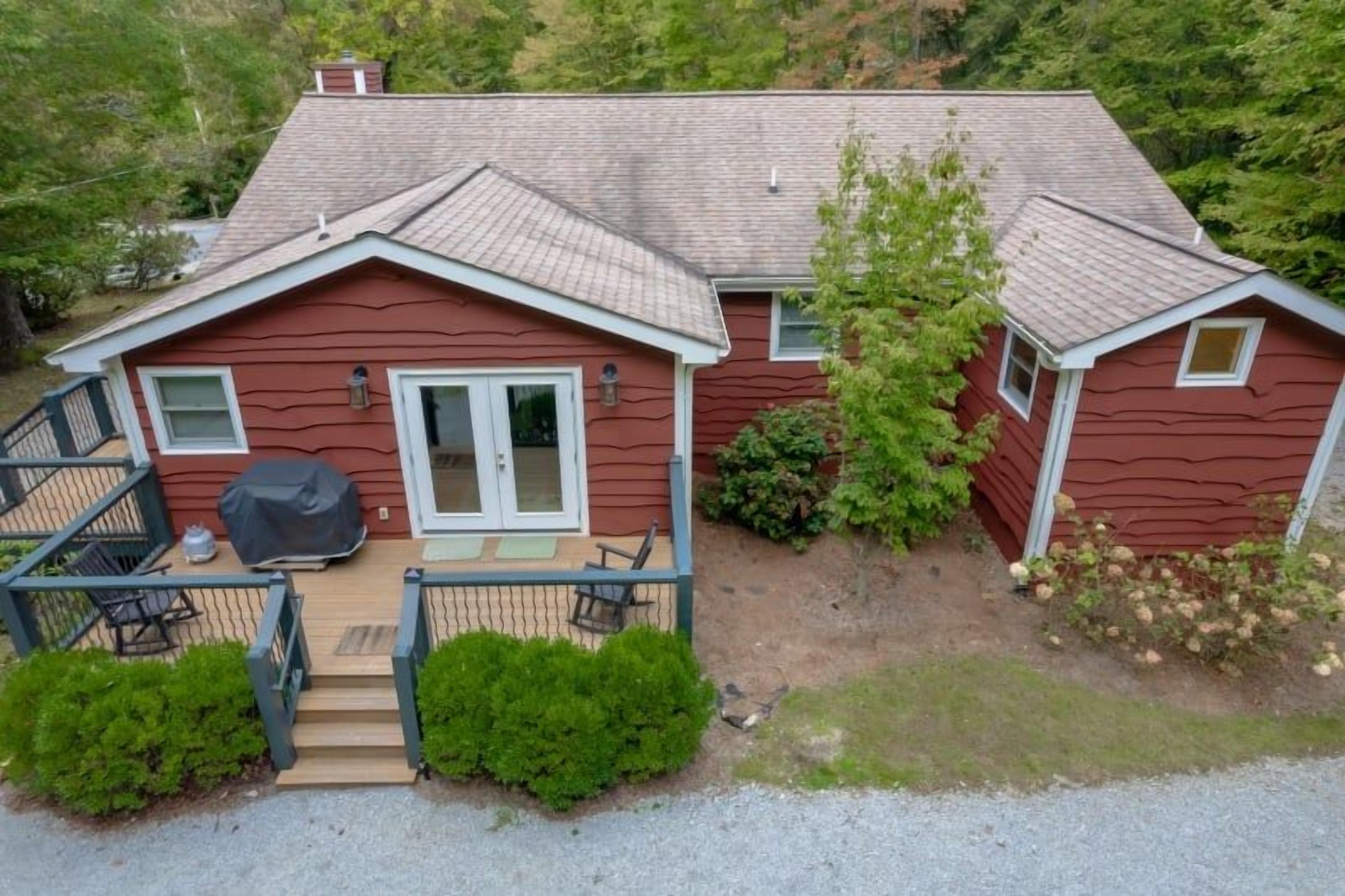 A two-story house with a covered patio, a front door, and a small deck.