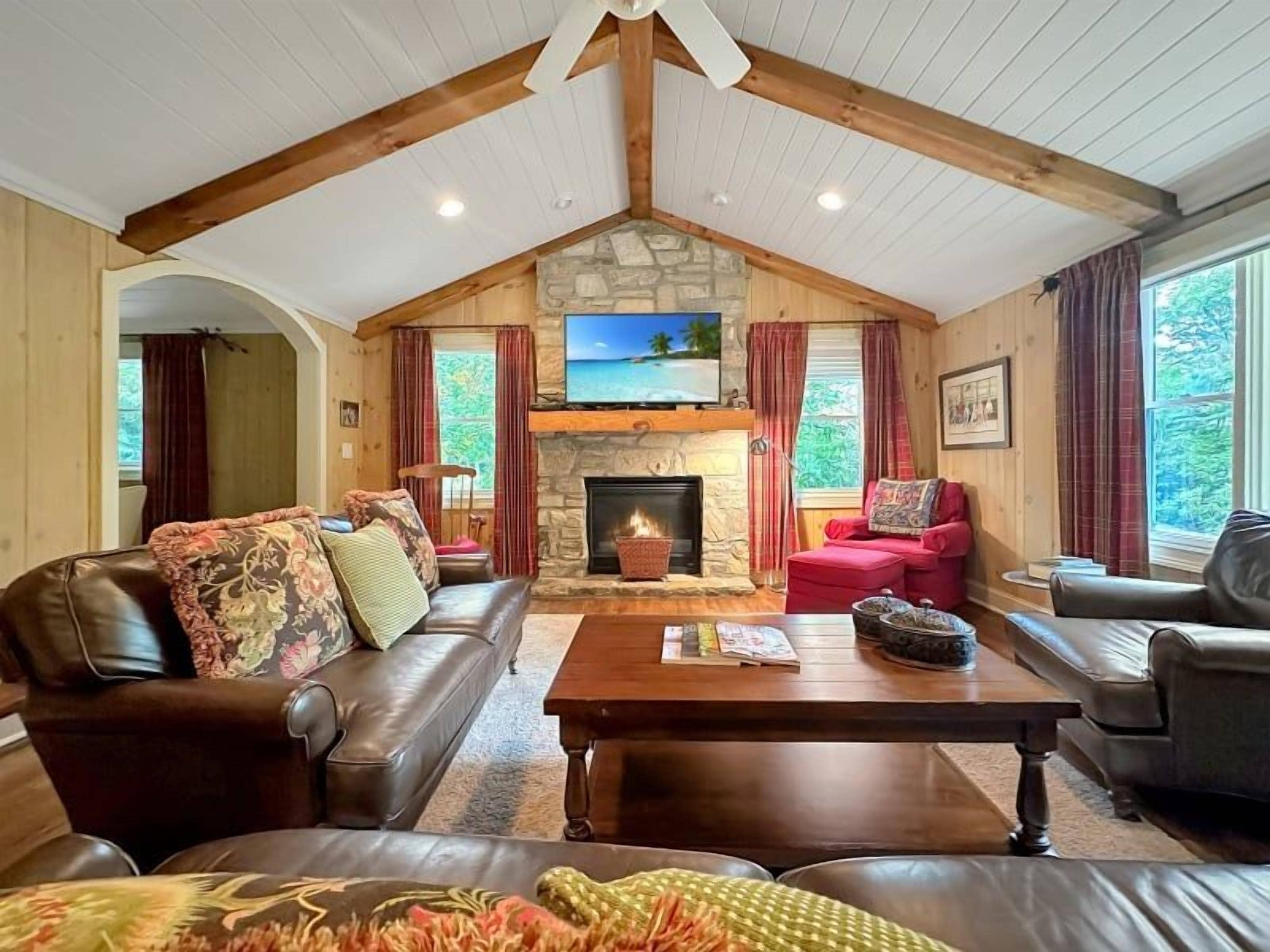 A cozy living room with a fireplace, leather sofas, and a stone wall.