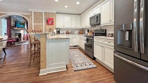 A modern kitchen with white cabinetry, stainless steel appliances, and a central island. - Walk to Dinner. Walk to Coffee. Walk to Everything | Wilson Cottage (Highlands)