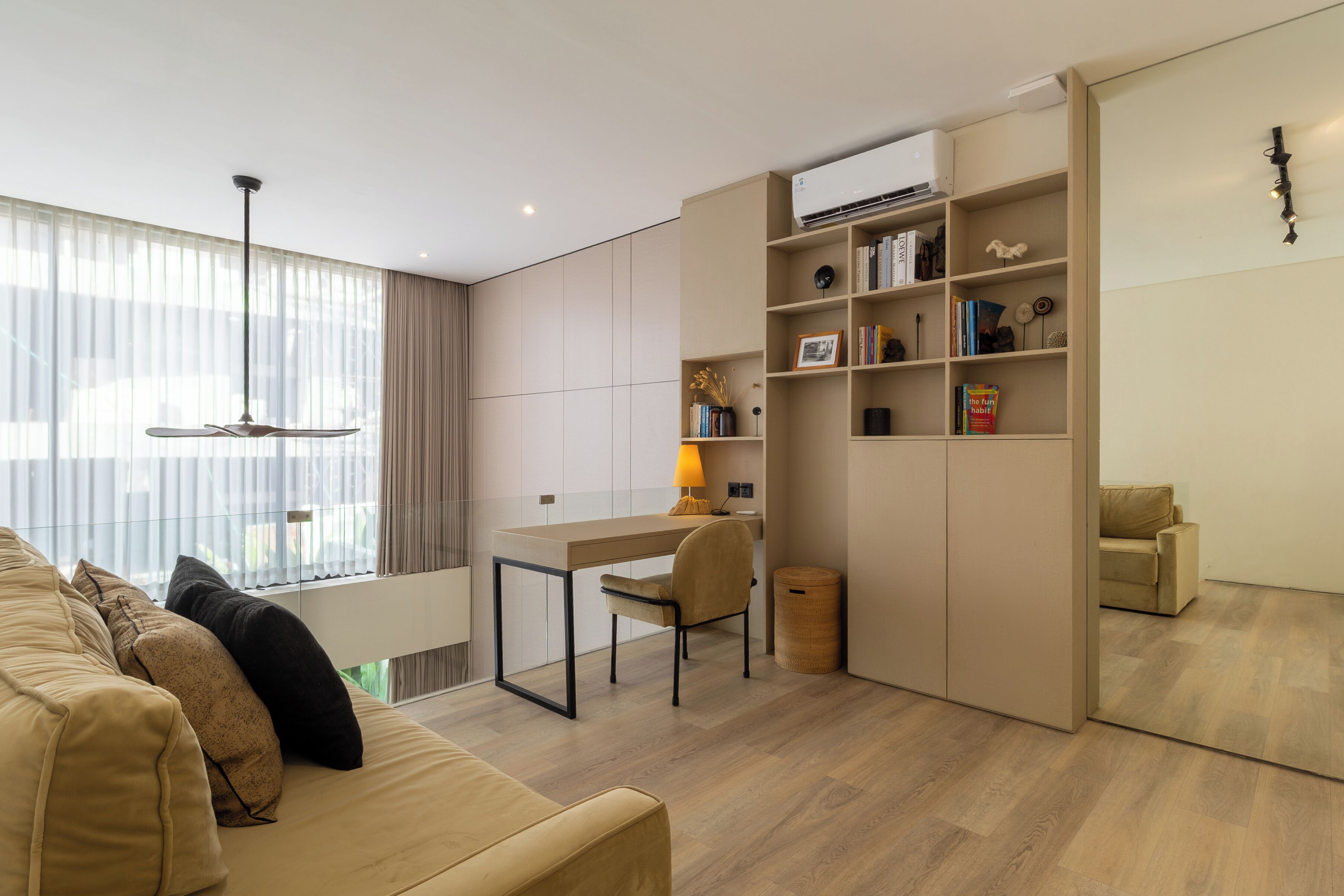 A modern living room with a sofa, a desk, and a bookshelf.