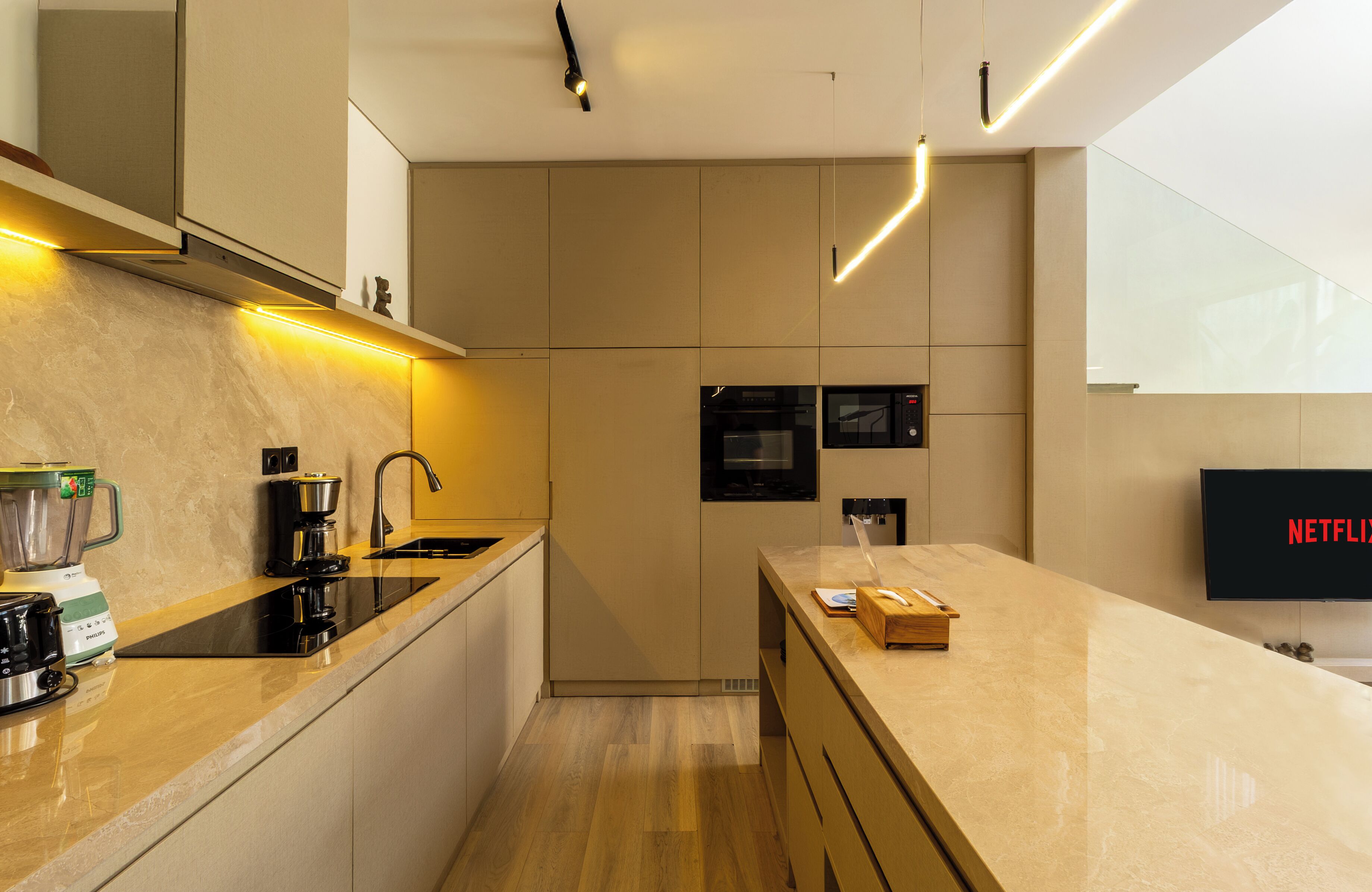 A modern kitchen with a built-in oven, a coffee maker, and a blender on the counter.