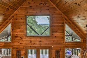 A wooden cabin with a large window offering a view of the forest. - Sunrise Overlook | Blue Ridge, GA (Blue Ridge)